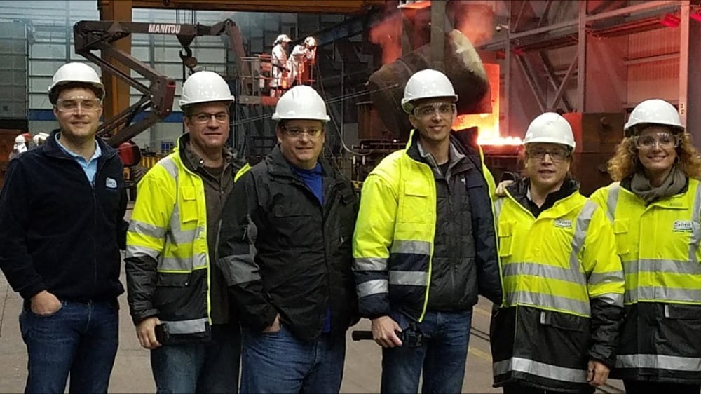 Group of people in black and yellow safety jackets on a factory floor