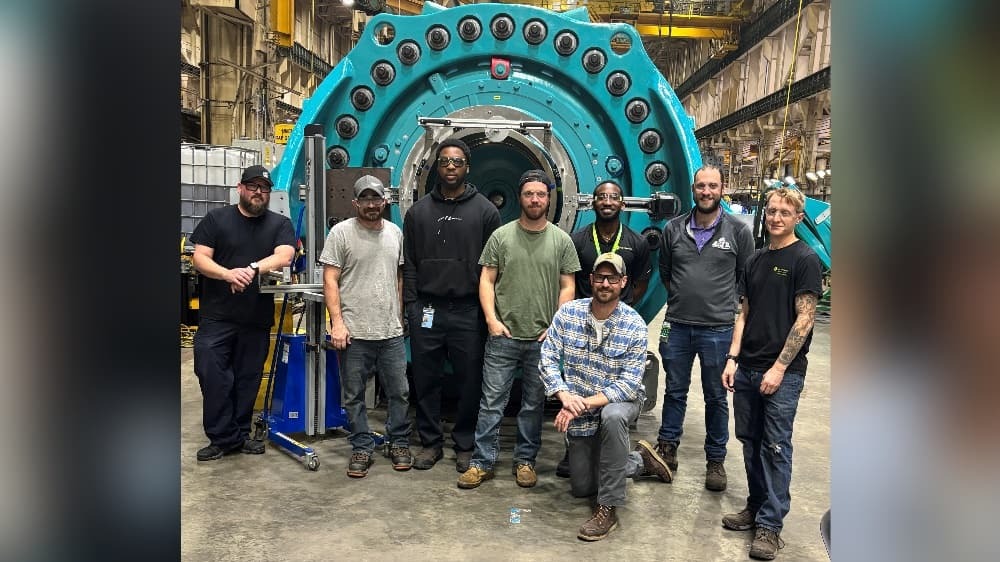 Group of men standing in front of a large piece of machinery